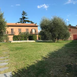 une grande maison avec une cour herbeuse devant elle dans l'établissement Agriturismo Azienda Agricola La Roccaia, à San Gimignano