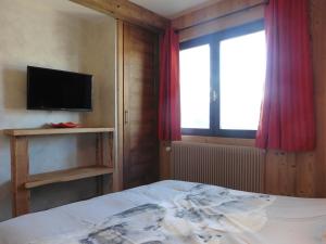 a bedroom with a bed and a tv and a window at Cozy chaleett on SLOPES in Crest-Voland