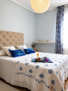 a bed with blue pillows and a tray of food on it at CAROLA l, "Encantador apartamento de estilo marinero a 100m playa Catia" in Ribeira