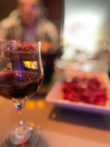 a glass of red wine next to a plate of food at Hidromassagem cromoterapia ar condicionado lareira in Imbé