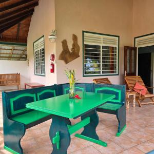 a green table and chairs in a patio at La Diguoise in La Digue