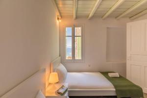 a white bedroom with a bed and a window at Serifos View in Serifos Chora