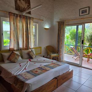 a bedroom with a large bed and a balcony at La Diguoise in La Digue +104 photos