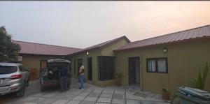 two people standing next to a house with their car with its trunk open at Rundu Rainbow Guesthouse in Rundu