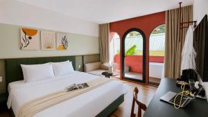 a bedroom with a bed and a desk and a window at Joi Boutique Bãi Trước in Vung Tau
