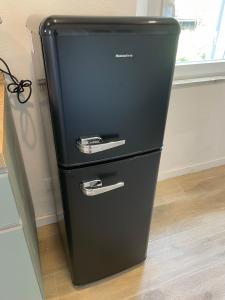 a black refrigerator is sitting in a room at SH Suite OLMO AC e Wi-Fi in Manziana