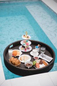 Ein Tablett mit Essen auf einem Tisch neben einem Schwimmbecken in der Unterkunft VEVILLA in Bangkok