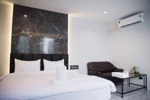 ein Schlafzimmer mit einem großen weißen Bett und einem Stuhl in der Unterkunft VEVILLA in Bangkok