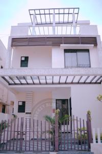 a white house with a fence in front of it at Breezy Classy Villa Mahabalipuram in Kelambākkam