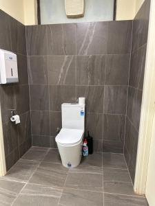 a bathroom with a toilet in a tiled wall at Workforce Accommodation in Kalgoorlie