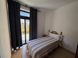 a bedroom with a bed and a large window at Bajo junto al mar en El Tamaduste in Tamaduste