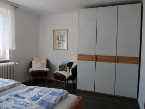 a bedroom with white cabinets and a bed and a chair at Haus Alpenblick in Immenstaad am Bodensee