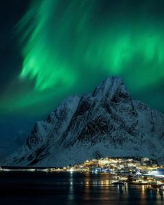 an image of a mountain with the northern lights at Astra Village - Waterfront Rorbu Cabins in Lofoten in Kabelvåg +42 photos