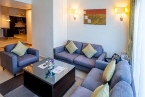 a living room with blue couches and a table at Imperial Suites Hotel in Doha