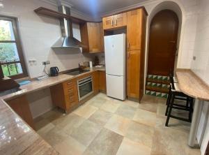 a kitchen with wooden cabinets and a white refrigerator at Garden Suites Xativa Casa Rural in Xàtiva