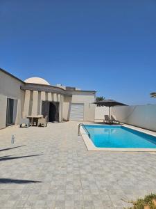 a swimming pool in front of a house at Villa Wissal Djerba piscine privée in Arkou