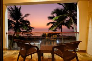 a balcony with a view of the ocean and palm trees at Sunlit Shores Beach Villa in Kundapur