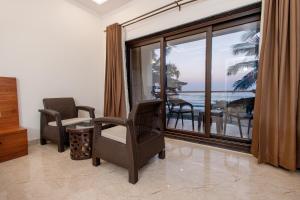a living room with chairs and a balcony with the ocean at Sunlit Shores Beach Villa in Kundapur