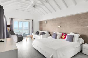 a white bedroom with a large bed and a couch at Hôtel Baie des Anges in Gustavia +16 photos
