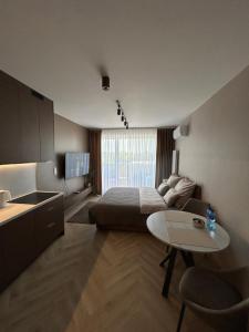 a bedroom with a bed and a table and a kitchen at Apartament Kaszmirowy in Nysa