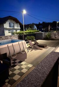 a patio with chairs and a swimming pool at night at Exclusive Una 4 in Bihać