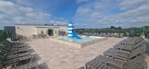 a pool with a blue and white lighthouse and chairs at Sea Apartments in Łeba