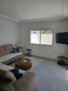 a living room with a couch and a flat screen tv at Villa Wissal Djerba piscine privée in Arkou