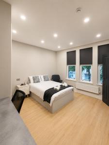 a white bedroom with a bed and two windows at 7 Bed, 7 BR Victorian Accom - Sleeps 14 in Walsall