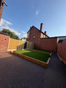 a backyard with a artificial lawn and a brick building at 7 Bed, 7 BR Victorian Accom - Sleeps 14 in Walsall