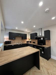 a large kitchen with black cabinets and wooden floors at 7 Bed, 7 BR Victorian Accom - Sleeps 14 in Walsall