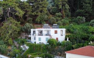 a white house on a hill with trees at Atlantis Rooms in Ágios Konstantínos