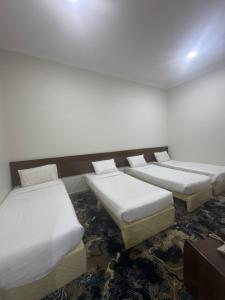 a room with three beds with white sheets at فندق بلورة البشاير in An Naqāʼ