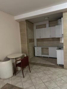 a kitchen with white cabinets and a table and chair at Kosvegas apartment 10 in Kosovo Polje