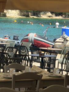 eine Gruppe von Stühlen und ein Boot im Wasser in der Unterkunft Tolos Budget Rooms Loggos in Longós