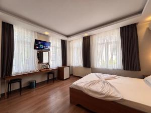 a bedroom with a bed and a desk and windows at Hisar Çeşme Hotel in Istanbul