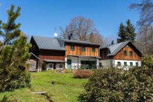 a large wooden house on a grassy field at Chata Rozhlas in Železná Ruda