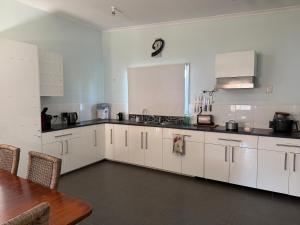 a kitchen with white cabinets and a wooden table at Opal St Homestay in Lightning Ridge