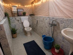 a bathroom with a toilet and a sink in a tent at Echoes in the Hills in Mukteshwar