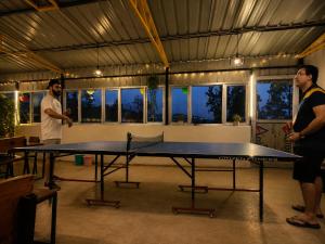 two men are standing around a ping pong table at Echoes in the Hills in Mukteshwar