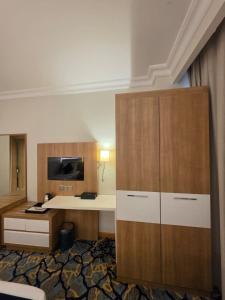 a hotel room with a desk and a cabinet at Al Madina Golden Hotel in Medina
