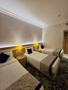 a hotel room with two beds and two lamps at Al Madina Golden Hotel in Medina