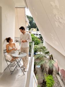 a man and a woman sitting at a table on a balcony at The Corfu Urban Stays in Ágios Rókkos