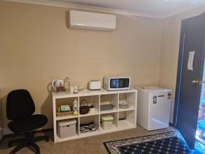a kitchen with a white refrigerator and a chair at Private Studio Ensuite & Kitchenette in Glen Waverley