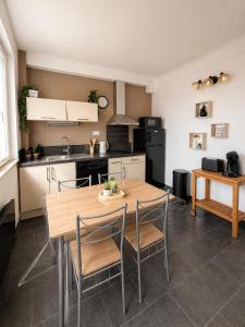 a kitchen with a wooden table and chairs in a room at L'éclat du phare in Calais