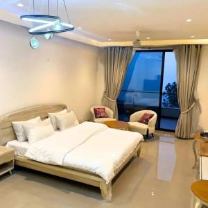 a bedroom with a large white bed and chairs at Park Ridge Hotel Serviced Apartments - Executive Apartment in Murree