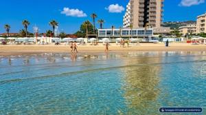 a group of people walking on the beach at Interno 132 in Porto San Giorgio