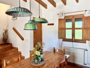 a dining room with a wooden table and pendant lights at Ses Oliveres in Cala Saona