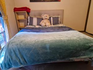 a teddy bear sitting on top of a bed at Private Studio Ensuite & Kitchenette in Glen Waverley