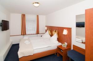 ein Hotelzimmer mit einem Bett und einem Spiegel in der Unterkunft Hotel -Restaurant Taormina in Birkenfeld