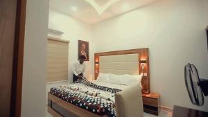 a man standing next to a bed in a room at Riverleaf Hotels and Suites in Asaba